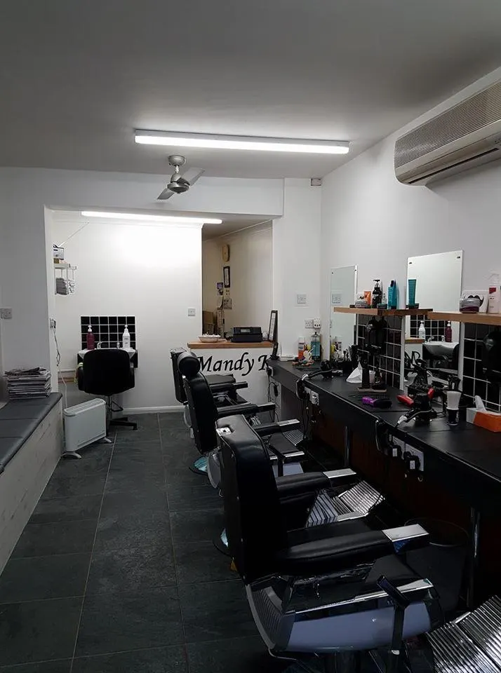 Inside Mandy K Barbers: a row of black barber chairs along the mirrors